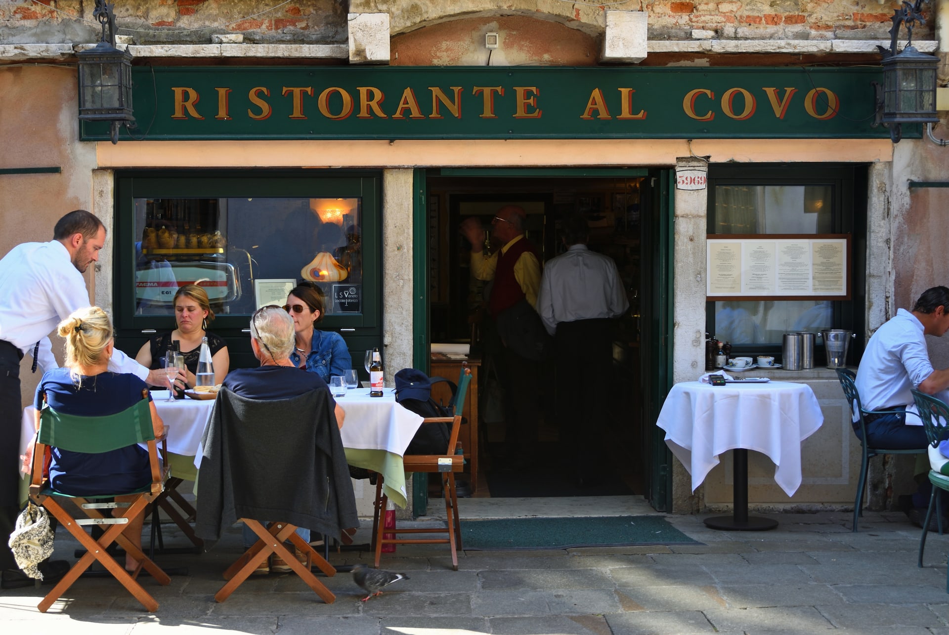 Façade du Ristorante Al Covo avec son enseigne verte et ses tables en terrasse, dans le quartier du Castello Façade du Ristorante Al Covo avec son enseigne verte et ses tables en terrasse, dans le quartier du Castello