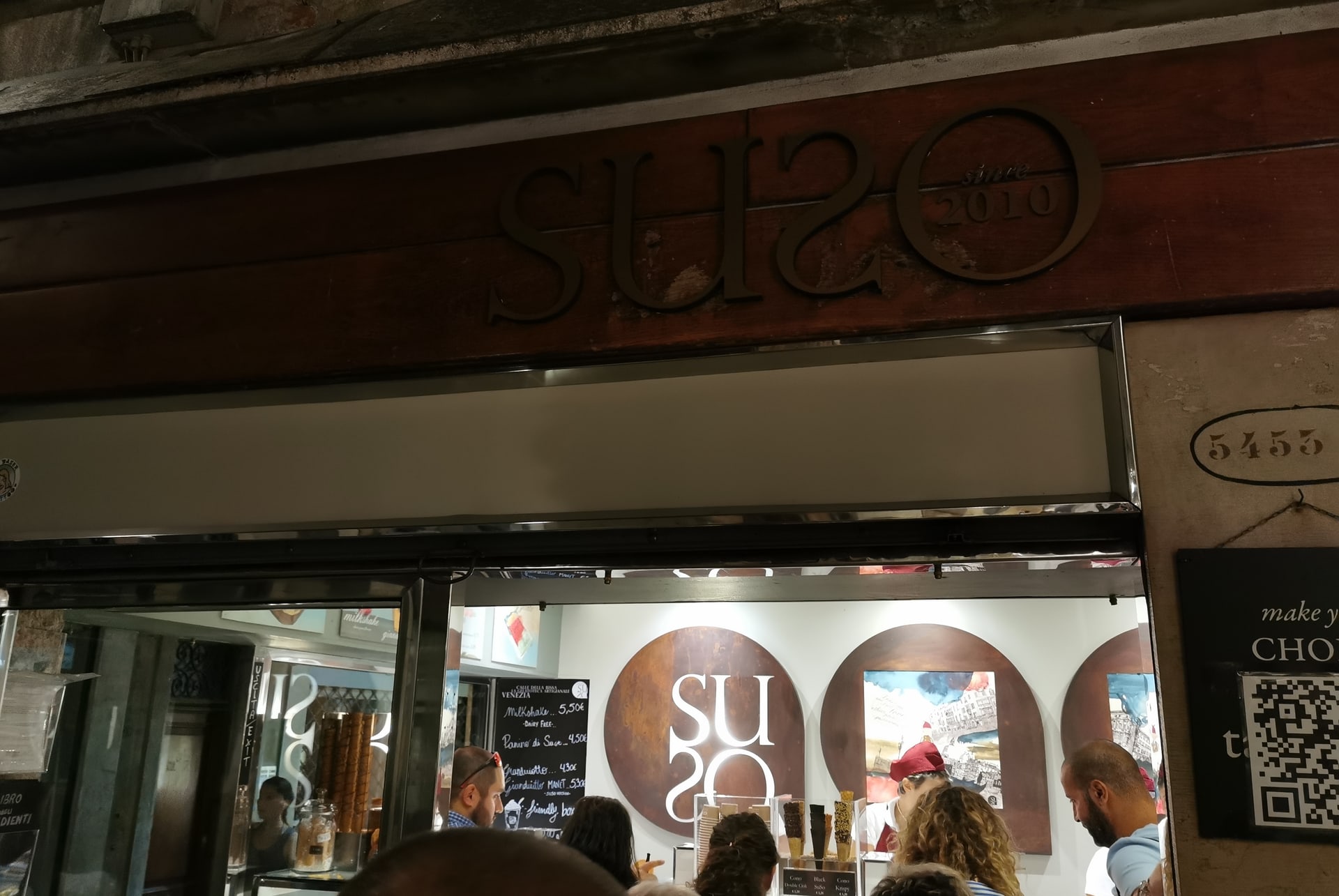 Devanture de la Suso Gelatoteca illuminée le soir, avec des clients au comptoir, près du Rialto à Venise Devanture de la Suso Gelatoteca illuminée le soir, avec des clients au comptoir, près du Rialto à Venise
